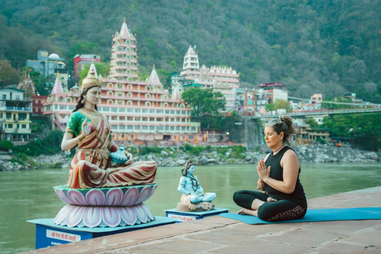 Woman doing yoga on the banks of river ganga in rishikesh